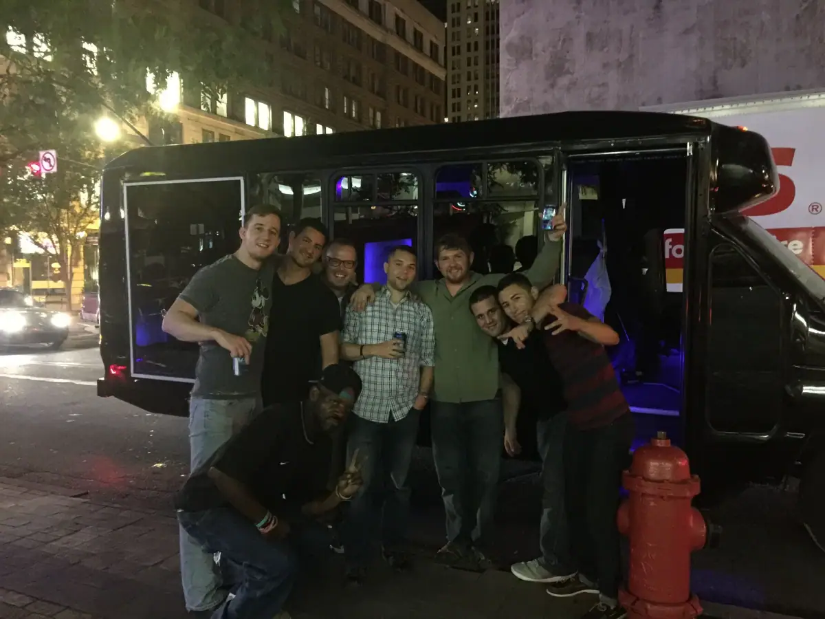 Group beside a black party bus at night