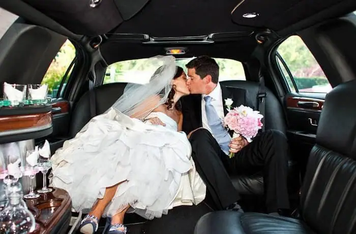 Bride and groom kissing in the back of a stretch limousine
