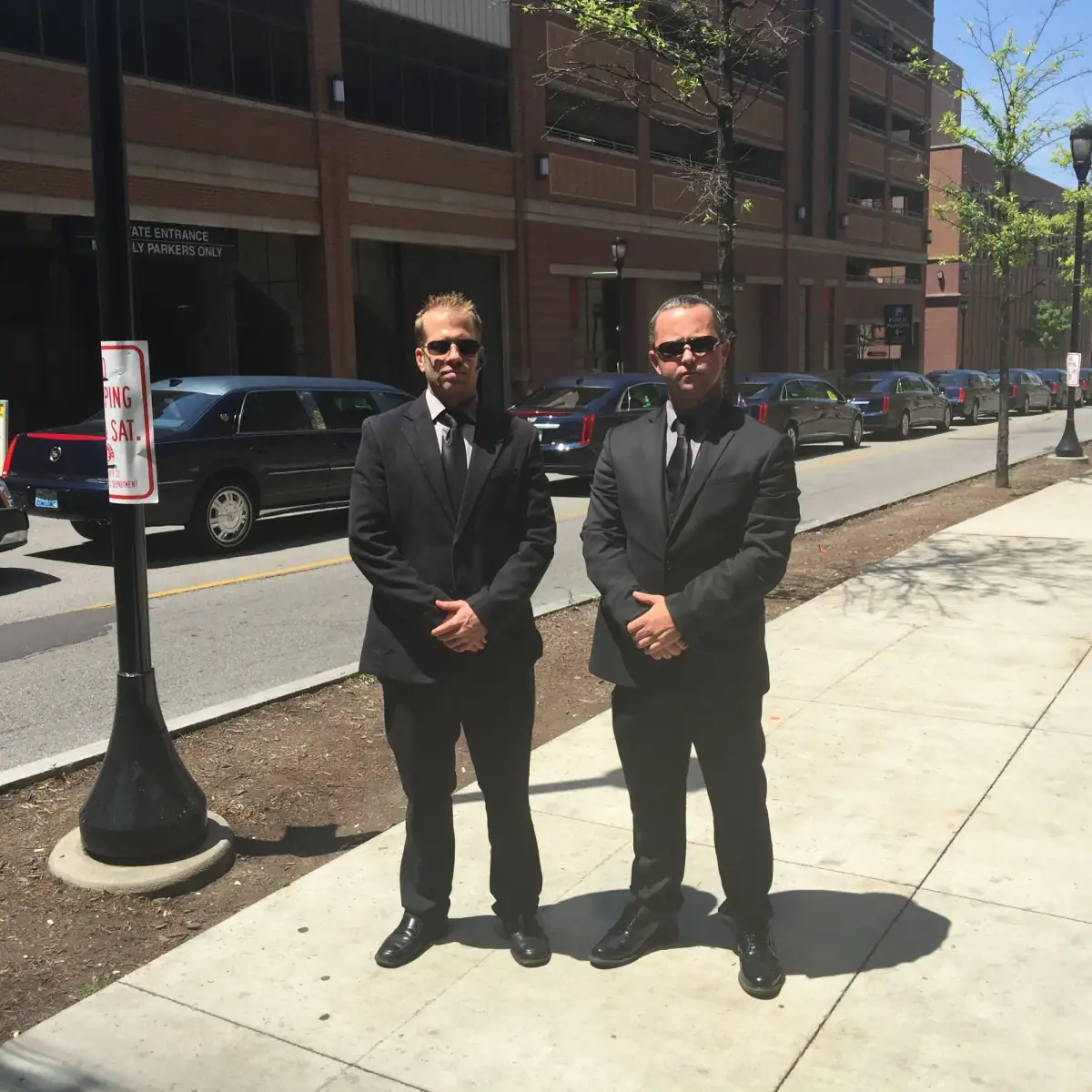 Two chauffeurs standing on a sidewalk