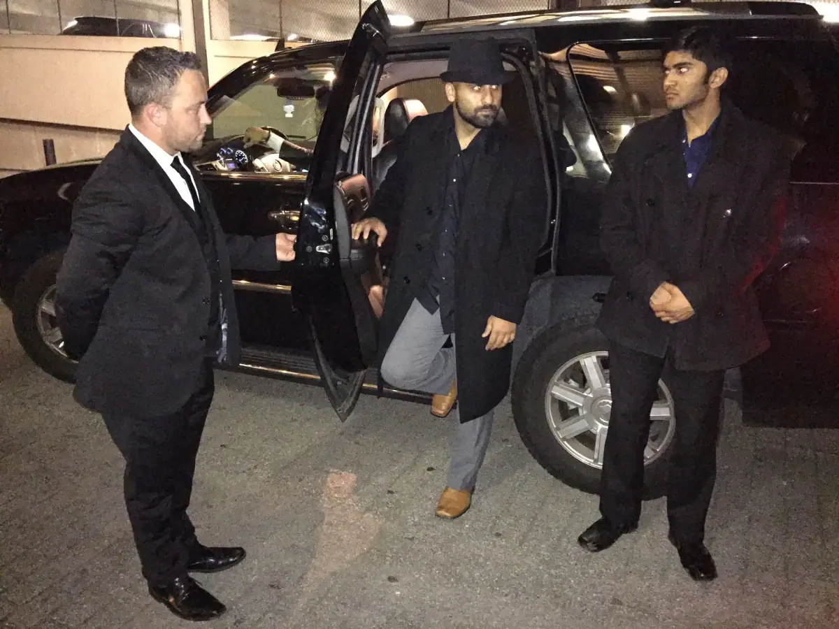 Chauffeur holding the door of a black SUV
