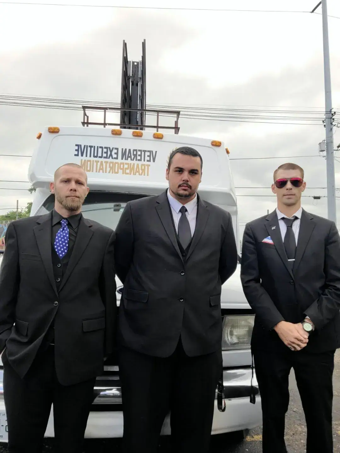 Three chauffeurs standing in front of a white shuttle bus