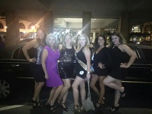 Bachelorette group beside a black stretch limousine at night