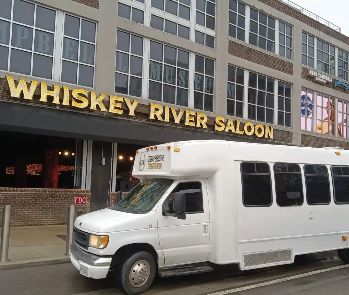 White VET shuttle at the curb on a downtown Louisville street