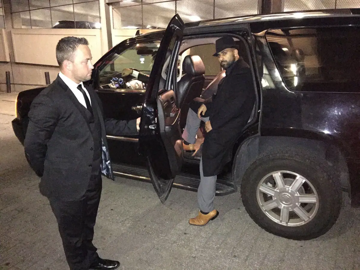 Chauffeur opening the door of a black SUV in an airport hangar