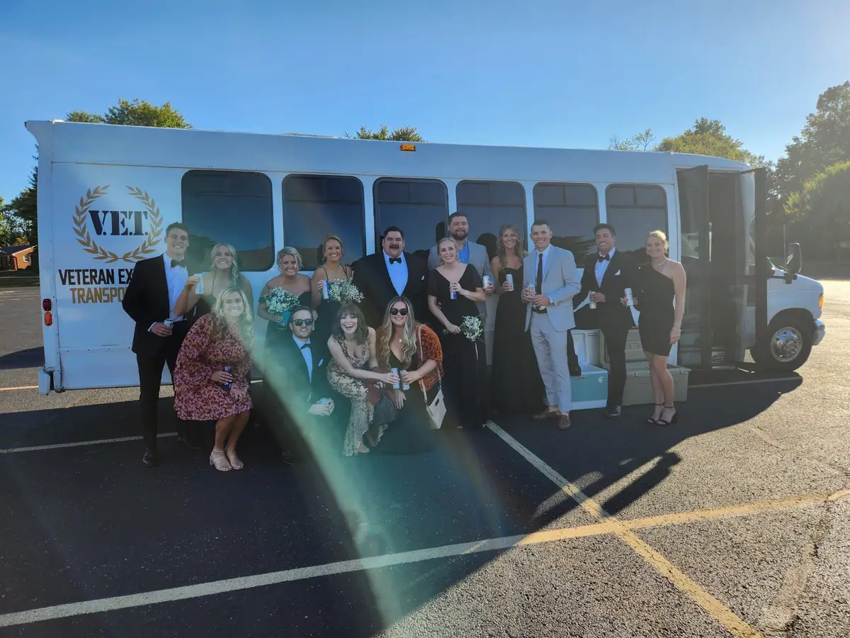 Wedding party in front of the white VET 30-passenger party bus